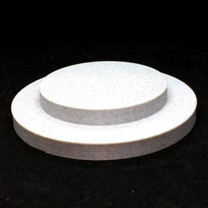 May include: Two white round platforms made of layered material, the top platform is smaller than the bottom platform.