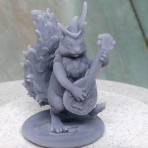May include: A grey figurine of a squirrel playing a banjo. The squirrel is wearing a hat and has a bushy tail. The banjo has a round body and a long neck. The figurine is on a round base.