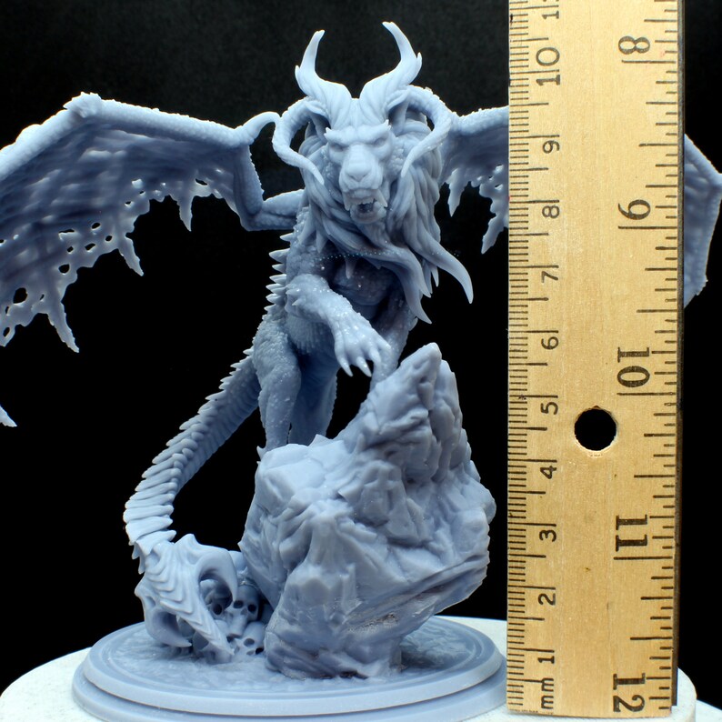 Puede incluir: Una miniatura gris de un le&oacute;n alado con una base rocosa, impresa en 3D. La miniatura mide aproximadamente 15 cm de alto.