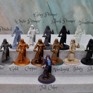 Puede incluir: Un conjunto de diez figuras en miniatura pintadas en varios colores, incluyendo plata, oro, cobre, verd&iacute;n, marfil y negro. Las figuras llevan todas t&uacute;nicas y sostienen una daga. Las figuras est&aacute;n etiquetadas con los nombres de los colores en los que est&aacute;n pintadas. El texto "Printed", "Gray Primer", "White Primer", "Black Primer", "Transparent", "Full Color" tambi&eacute;n es visible en la imagen.
