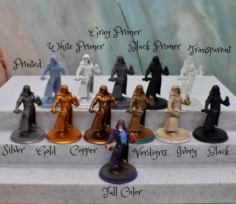 Puede incluir: Un conjunto de diez figuras en miniatura pintadas en varios colores, incluyendo plata, oro, cobre, verd&iacute;n, marfil y negro. Las figuras llevan todas t&uacute;nicas y sostienen una daga. Las figuras est&aacute;n etiquetadas con los nombres de los colores en los que est&aacute;n pintadas. El texto "Printed", "Gray Primer", "White Primer", "Black Primer", "Transparent", "Full Color" tambi&eacute;n es visible en la imagen.