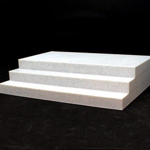 May include: Three white steps made of a textured material, resembling a small staircase.
