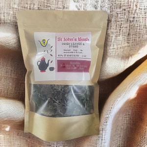 Könnte beinhalten: Ein Kraftpapierbeutel mit transparentem Fenster, gefüllt mit getrockneten Blättern und Stängeln. Das Etikett trägt die Aufschrift "St John's Bush Dried Leaves & Stems" mit einer Grafik einer Teekanne und Tasse. Der Text gibt die Herkunft aus St. Lucia an.