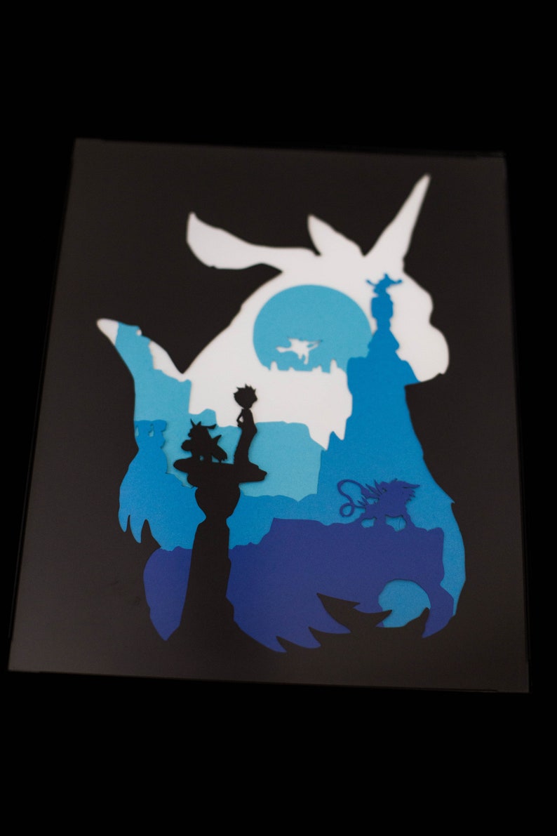 May include: A paper cut-out silhouette of a unicorn with a blue and white color scheme. The unicorn is standing on a blue and white landscape with a small figure standing on a tower.