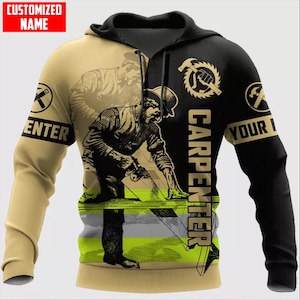 Op de afbeelding: Een sweatshirt met lange mouwen en capuchon met een gespleten beige en zwart ontwerp. De afbeelding toont een timmerman die een zaag gebruikt, met de tekst "CARPENTER" verticaal gedrukt. Een "CUSTOMIZED NAME"-label staat linksboven en cirkelvormige gereedschapspictogrammen staan op de mouwen.