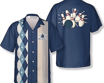 Pode incluir: Camisa de boliche azul marinho com um design frontal com um padrão de losangos e um gráfico de pinos de boliche. A parte de trás da camisa exibe uma bola de boliche e pinos. A camisa tem uma frente abotoada e uma gola. O nome "MICHAEL" é impresso na frente.
