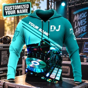 Op de afbeelding: Een turquoise hoodie met een afbeelding van een DJ-mengpaneel en een koptelefoon. De tekst "YOUR NAME" staat diagonaal op de borst gedrukt, met "DJ" en een silhouetpictogram erboven. De mouwen zijn voorzien van kleine koptelefoonafbeeldingen.