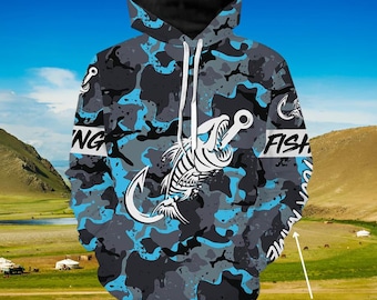 Könnte beinhalten: Ein blauer und grauer Camouflage-Hoodie mit einem weißen Fischskelett und einem Haken-Motiv. Der Hoodie hat einen weißen Kordelzug und den Text "Fishing" und "Fish" auf den Ärmeln. Der Text "Custom Text" befindet sich in der unteren rechten Ecke des Bildes.
