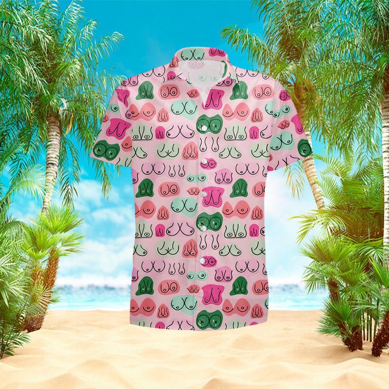 May include: A short-sleeved button-down shirt with a pink background and a repeating pattern of stylized breasts in various colors, including green, pink, and blue. The shirt has a classic collar and a relaxed fit, suitable for casual wear.