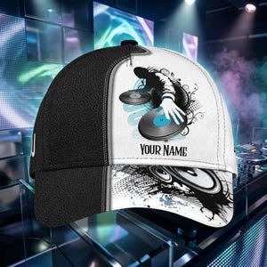 Puede incluir: Una gorra de béisbol con un diseño dividido en un lado negro sólido y otro blanco. La sección blanca muestra un gráfico de la silueta de un DJ con discos de vinilo, detalles en azul y el texto "YOUR NAME" sobre la ilustración de un altavoz.
