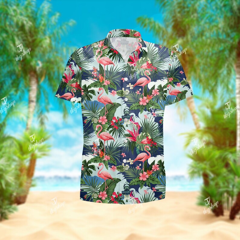 May include: A short-sleeve button-down shirt featuring a repeating pattern of pink flamingos, green palm leaves, and red hibiscus flowers against a light blue background with dark blue horizontal stripes throughout the garment.