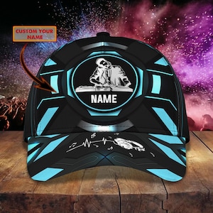 Peut inclure: Casquette de baseball noire avec un graphisme de DJ dans un ovale bleu et blanc. La casquette présente un design géométrique avec des accents bleus. Le texte "CUSTOM YOUR NAME" est au-dessus et "NAME" en dessous.