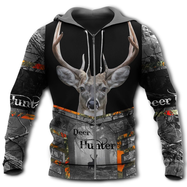 May include: A black and gray zip-up hoodie featuring a large deer head graphic on the chest, a forest scene with a silhouette of a deer, and the text "Deer Hunter" printed on the front. The sleeves and lower body have a camouflage pattern.