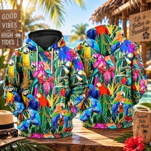 Peut inclure: Un sweat à capuche arborant un imprimé intégral vibrant de perroquets colorés, incluant des aras et des toucans, nichés parmi des feuilles tropicales vert luxuriant et des fleurs roses. Le vêtement possède une doublure noire et des cordons blancs.