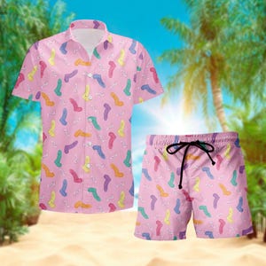 May include: Pink button-up shirt and matching shorts with a colorful cartoon pattern.