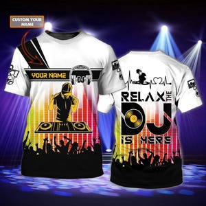 May include: White t-shirt with a DJ theme. The front features a DJ graphic, the text "YOUR NAME", and a silhouette of a DJ. The back of the shirt says "RELAX THE DJ IS HERE" with a heartbeat graphic.