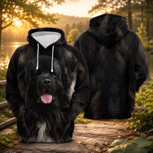 Könnte beinhalten: Ein schwarzer Kapuzenpullover mit einer großen, realistischen Grafik eines Neufundländer-Hundegesichts mit herausgestreckter Zunge auf der Vorderseite. Das Kleidungsstück hat eine Kapuze mit weißen Kordeln und weißem Innenfutter.