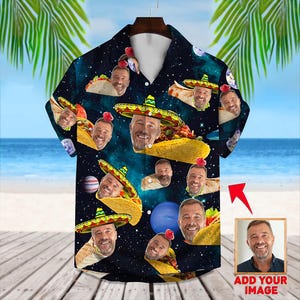 Puede incluir: Una camisa negra de botones con un estampado de temática espacial con caras y tacos. La camisa tiene un cuello de botones y mangas cortas. El estampado incluye una variedad de caras con diferentes expresiones, todas con sombreros. Los tacos están rellenos de varios ingredientes, incluyendo carne, queso y verduras. La camisa tiene un bolsillo en el lado izquierdo. El texto "Añadir tu imagen" es visible en la esquina inferior derecha de la imagen.