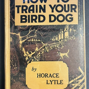 May include: A vintage book cover with the title "HOW TO TRAIN YOUR BIRD DOG" by Horace Lytle. The cover illustration depicts a dog in a field with a wooden fence and trees, in shades of brown and tan. The title is in bold black letters.