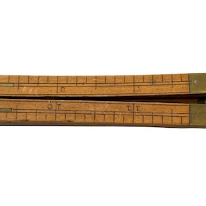 May include: A vintage wooden folding ruler with brass-plated ends. The ruler is light brown with black markings and numbers. The ruler is folded in half, showing the measurement markings. The ruler measures approximately 30 cm when fully extended.