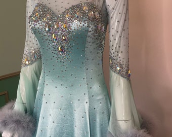 May include: A light blue dance dress with a sheer overlay and long sleeves. The dress is embellished with rhinestones and has a feathered trim at the cuffs.