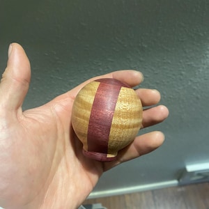 May include: A wooden sphere with a purple and brown striped pattern.
