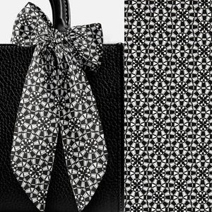 May include: A black leather tote bag with a decorative bow. The bow and a portion of the bag feature a repeating geometric pattern in black and white. The pattern is also shown on the right side of the image.