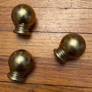 May include: Three spherical finials with a smooth, metallic gold finish. Each finial features a rounded top section and a tiered, cylindrical base with horizontal ridges, providing a consistent design across all three individual pieces.