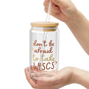 May include: A clear glass jar with a wooden lid and a straw. The jar has the text "don't be afraid to take risks" printed on it.