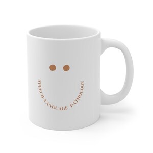 May include: White ceramic coffee mug with a brown smiley face and the text "Speech-Language Pathology" around the bottom of the mug.