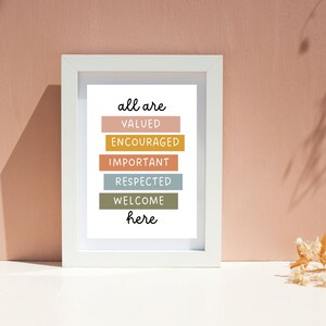 May include: White framed print with the text "all are valued encouraged important respected welcome here" in black lettering. Each word is on a separate colored rectangle. The colors are peach, yellow, light blue, green, and brown.