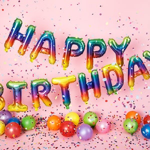 May include: Rainbow foil letter balloons spelling "Happy Birthday" against a pink background with confetti.