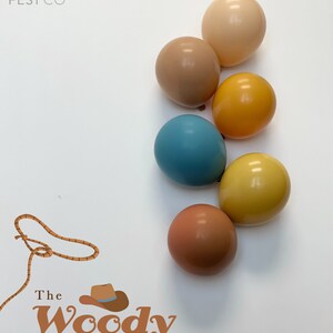 May include: A set of seven balloons in various shades of brown, yellow, and blue. The balloons are arranged in a semi-circle on a white background. The text "POP FEST CO" and "The Woody collection" is visible in the image.