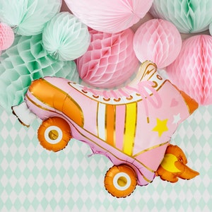 May include: Pink and orange roller skate shaped balloon with a yellow star and a white heart. The balloon is surrounded by pink and green honeycomb tissue paper balls.