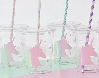 May include: Clear plastic cups with lids, each featuring a pink unicorn silhouette and star accents. The cups have colorful straws with polka dots, chevron, and striped patterns. Perfect for a unicorn-themed party or event.