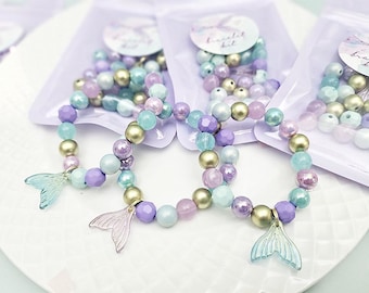 May include: Three mermaid-themed bracelets made with pastel blue, purple, and gold beads. Each bracelet has a mermaid tail charm.