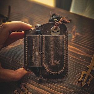May include: A brown leather wallet with a skull keychain, a pen, and the text "Leather Goods" and "TCM".