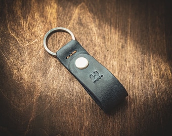 May include: Black leather key chain with a silver ring and a small metal tag that says "Hand Made".