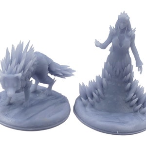 Könnte beinhalten: Ein 3D-gedrucktes Miniatur-Set mit einer weiblichen Figur mit Krone und einem Wolf, beide mit Eiskristallen bedeckt. Die Figuren stehen auf runden Sockeln.
