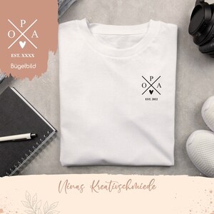 Könnte beinhalten: Weißes T-Shirt mit einem schwarz-weißen Logo-Design, das die Buchstaben "P", "O" und "A" in Kreuzform mit einem kleinen Herzen in der Mitte zeigt. Der Text "EST. 2022" befindet sich unter dem Logo. Der Text "Ninas Kreativschmiede" befindet sich am unteren Rand des Bildes.