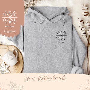 Könnte beinhalten: Grauer Kapuzenpullover mit einem schwarzen Grafikdesign eines Kreuzes mit den Buchstaben N, K, E, O und L darum herum. Die Grafik enthält auch ein kleines Herz und den Text "EST. 2024".