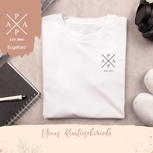 Könnte beinhalten: Weißes T-Shirt mit einem schwarzen Logo auf der Vorderseite. Das Logo ist ein stilisierter Buchstabe "P" mit zwei "A"s auf jeder Seite, alles in einem Quadrat. Der Text "EST. 2019" befindet sich unter dem Logo.