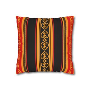 Könnte beinhalten: Quadratisches Zierkissen mit schwarzem Hintergrund und vertikalen Streifen in Orange, Rot und Gold. Der Mittelstreifen weist ein sich wiederholendes herzförmiges Design auf. Die Ränder haben eine gemusterte Bordüre.