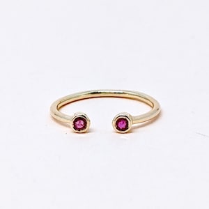 May include: A gold ring with two small red gemstones on the ends.