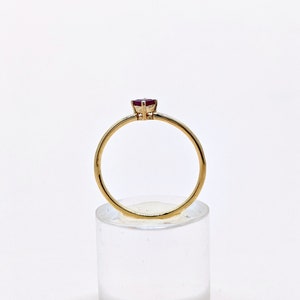 May include: A gold ring with a single red gemstone set in the center.