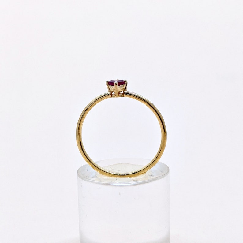 May include: A gold ring with a single red gemstone set in the center.