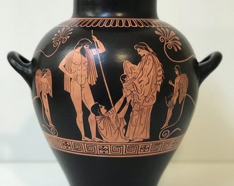 May include: Black and red Greek amphora vase with a scene of figures painted on the side. The figures are in red and are outlined in black. The vase has two handles.