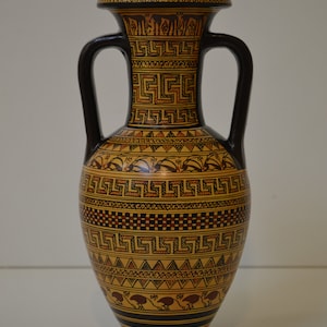 May include: A black and brown ceramic amphora with geometric patterns and bird designs. The amphora has two handles and a narrow neck.