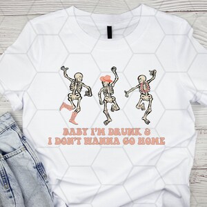 May include: White t-shirt with a graphic of three skeletons dancing. The skeletons are wearing cowboy hats and boots. The text "Baby I'm Drunk & I Don't Wanna Go Home" is printed below the skeletons.