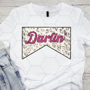 Op de afbeelding: Wit T-shirt met een grijze en witte luipaardprintbanner met de tekst "Darlin'" in roze.